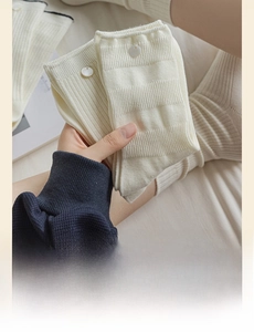 Detail of cream ribbed socks featuring scalloped edges and decorative side buttons