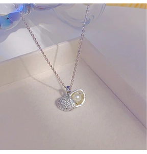 Close-up of shell pendant necklace with sparkling pavé crystals and a white center pearl