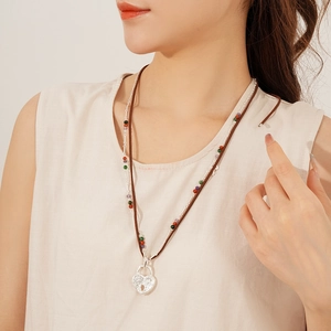 Detail of a double-layer heart lock necklace with colorful beads on a brown cord