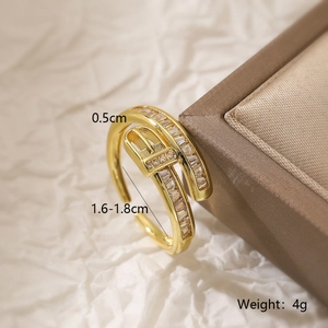 Detailed view of gold buckle ring with cubic zirconia on textured paper with size specs