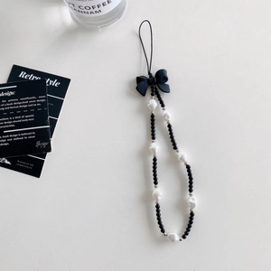 Detail of beaded phone strap with black bow, white faux pearls and silver spacers