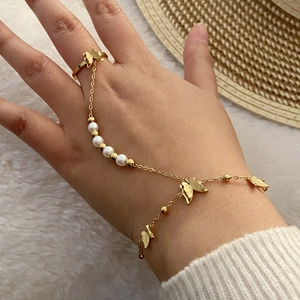 Dettaglio del bracciale anello a farfalla dorato con perle bianche sulla mano