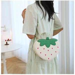 Lifestyle view of a strawberry shaped crossbody bag with sequined green leaf detail