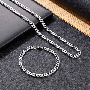 Ensemble collier et bracelet à maille gourmette en acier inoxydable argenté poli sur fond noir