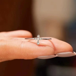 Close-up of minimalist silver cross ring with micro-set zircon stones on finger
