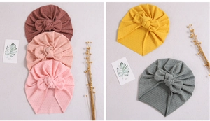 Flat lay of soft baby turbans with decorative bows in brown, pink, yellow, and grey colors