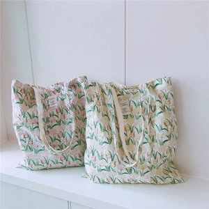 Detailansicht von zwei Baumwolltaschen mit pastellfarbenem Tulpenmuster und Stoffetiketten