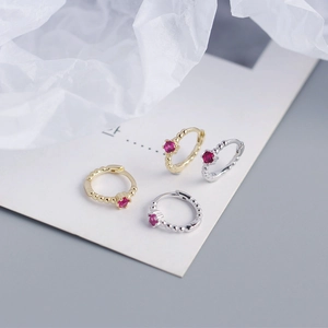 Close-up of gold and silver S925 sterling silver hoop earrings with red zircon stones