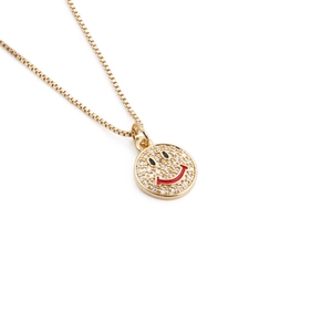 Detail of gold necklace with zircon smiley pendant and red enamel smile