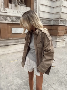Detail of brown suede leather jacket with pocket accents and vintage stone background