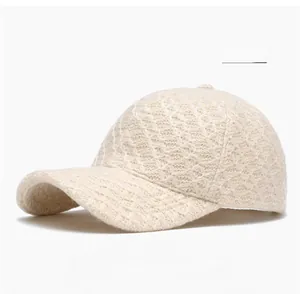 Detailed close-up of a beige knitted lace baseball cap featuring intricate hollow patterns
