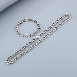 Detail of silver stainless steel weave chain necklace and bracelet set on gray surface