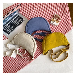 Detailed top view of nylon crescent crossbody bags in blue, beige, and yellow on picnic mat