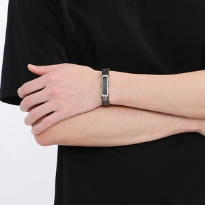 Dettaglio del design a cavo intrecciato e piastrina ID su un bracciale in acciaio scuro