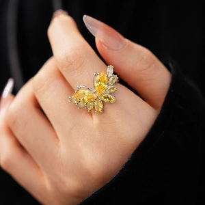 Détail macro d'une bague papillon argentée ornée de pierres jaunes taille marquise