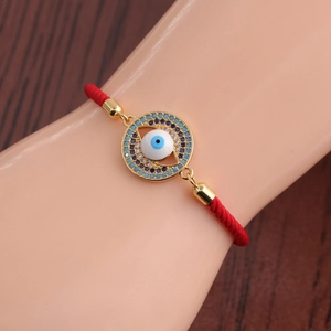 Macro detail of red woven Evil Eye bracelet with blue and white cubic zirconia stones
