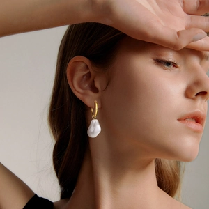 Detail view of a vintage gold knot earring with a natural baroque pearl on model