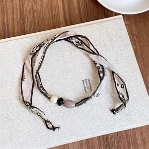 Collana vintage in tessuto paisley con tre perline su un libro per uno stile estetico elegante