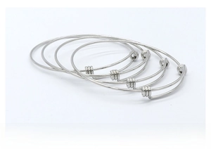 Macro view of five silver adjustable stainless steel bracelets with polished metal finish