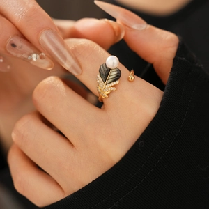Detail view of gold feathered shell ring with small pearl and zircons on finger