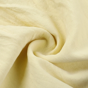 Détail du tissu en coton et lin beige avec des plis en spirale et texture tissée