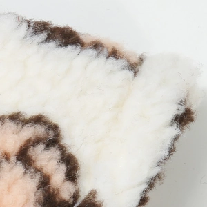 Macro detail of plush faux fur texture showing soft white and brown fiber stitching