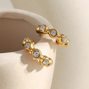 Close-up of 18K gold plated hoop earrings with cubic zirconia on a ceramic vase
