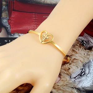 Close-up of golden stainless steel heart cross bracelet worn by a model on wrist