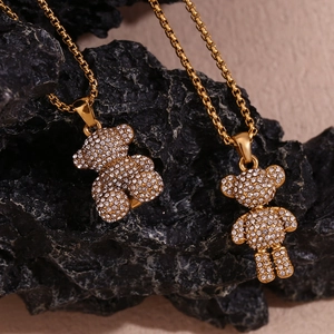 Detail of two gold-plated bear pendants with white rhinestones on natural rock