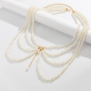Macro view of multi-layer pearl body chain showing gold lobster clasp and teardrop charm