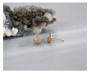 Macro shot of gold mushroom earrings with micro-set white zircon and polished texture