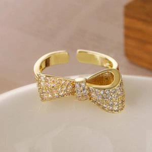 Elegant 18K gold-plated bow-shaped open ring with cubic zirconia on a white plate