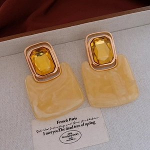 Detailed macro view of vintage gold earrings with yellow resin and crystal elements