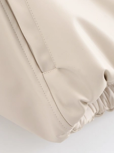 Macro view of cream faux leather texture with fine stitching and elastic hem detail