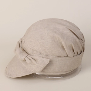 Detail view of light beige linen newsboy cap with a side bow and textured fabric finish