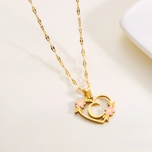 Close-up of heart-shaped stainless steel necklace with letter C and floral detail