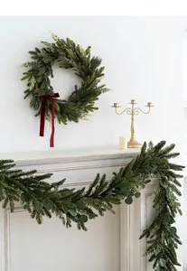 Close-up of artificial PE Christmas wreath and garland set on a white mantel fireplace