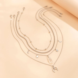 Detail of layered silver necklaces with star, moon charms and rhinestone tassels