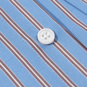 Macro detail of blue striped fabric texture and white resin button on loose shirt