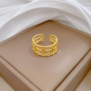 Vue macro d'une bague trèfle dorée ajourée posée sur un écrin à bijoux marron