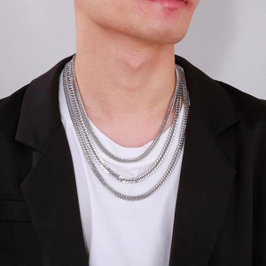 Close-up of a silver multi-layered Cuban chain necklace on a model wearing a suit