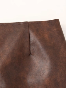 Détail de la jupe en similicuir marron montrant les coutures précises et la texture mate