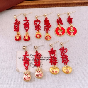 Detail of red and gold Chinese New Year earrings with lucky charms on white linen