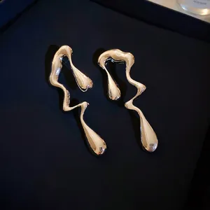Macro shot of liquid metal irregular wave earrings with silver mirror finish on box