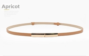 Detail of slim apricot patent leather belt with gold metal buckle and tonal stitching