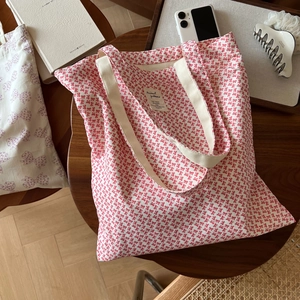 Détail du sac cabas en toile à motif de nœuds rouges avec poignées en coton