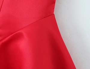 Close-up of the red satin fabric showing smooth texture and premium glossy finish on dress