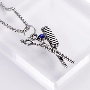 Detailed macro view of vintage stainless steel barber scissors comb pendant with blue crystal