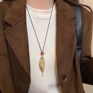 Close-up of golden leaf pendant necklace with amber bead on professional attire