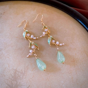 Détail de boucles d'oreilles muguet élégantes avec feuilles vertes et gouttes d'eau